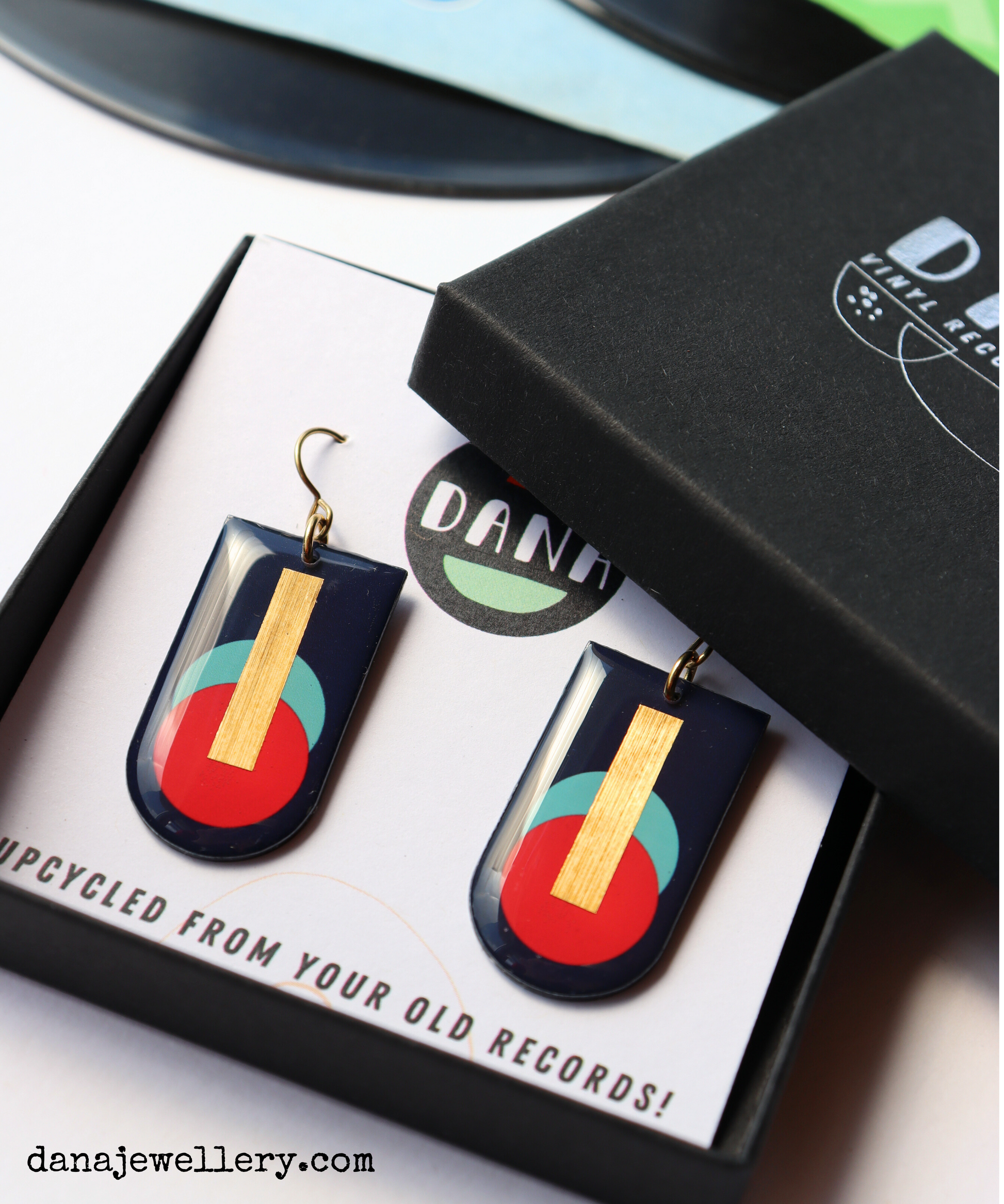 A pair of abstract geometric earrings handmade in Ireland from recycled vinyl records, featuring deep navy, red, and blue-green colours with a gold accent.
