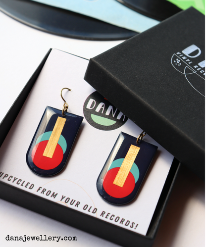 A pair of abstract geometric earrings handmade in Ireland from recycled vinyl records, featuring deep navy, red, and blue-green colours with a gold accent.
