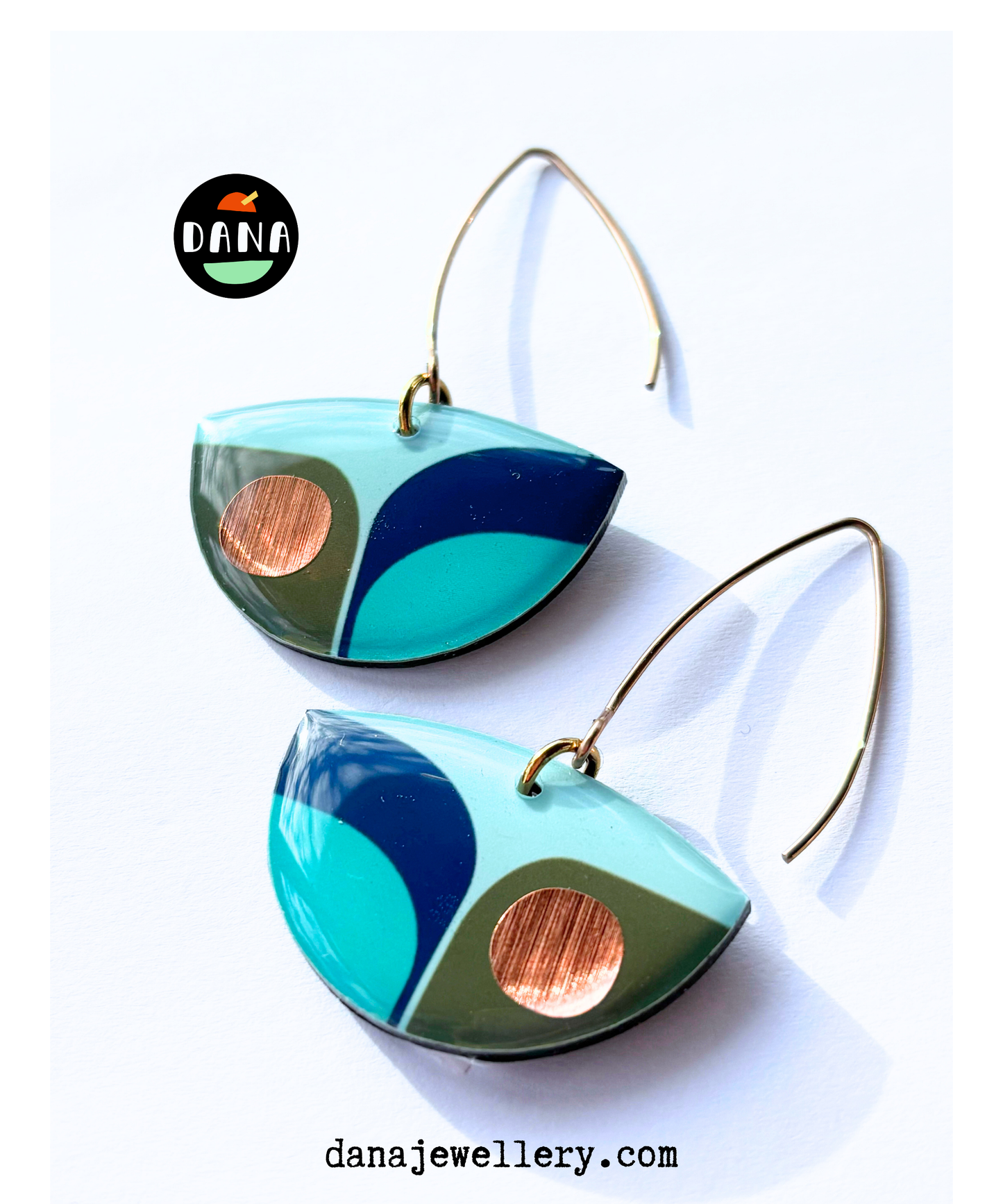 A pair of retro inspired drop earrings featuring geometric patterns in blue, green, and teal colours with copper accents with long stylish hooks, made in Ireland from recycled vinyl record, displayed against a white background.