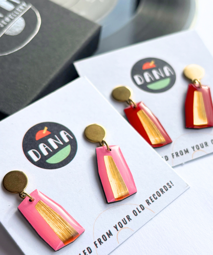 Modern minimalist colourful earrings handmade in Ireland in pink, red and gold attached to gold-colored posts, displayed on a clear surface 