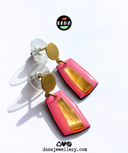 Pink and gold odern minimalist earrings handmade in Ireland attached to gold-colored posts, displayed on a clear surface 